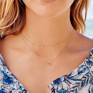 Double-layered gold necklace with diamond and circular pave pendants on model collarbone