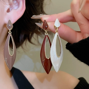 Macro view of teardrop hollow geometric earrings in plum, red and pearly white finish