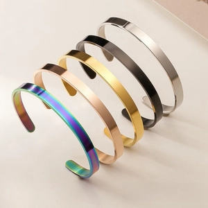 Close-up of C-shaped matte cuff bracelets in five metallic colors on beige background