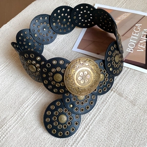Detail of vintage bohemian belt with black round studs and embossed floral metal buckle