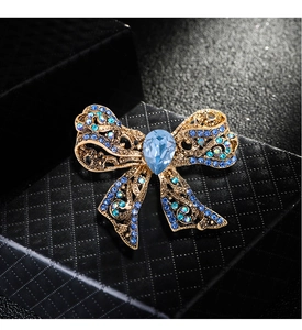 Macro shot of luxury gold bow brooch with blue crystals on a textured black gift box