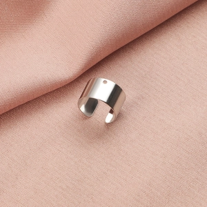 Macro detail of a polished silver stainless steel open ring accessory with a small hole