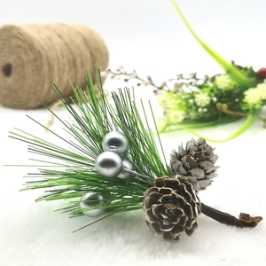 Artificial pine branch with green needles, silver berries and frosted pine cones