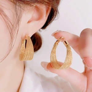 Macro detail of golden multi-layer mesh braided hoop earrings with metallic texture