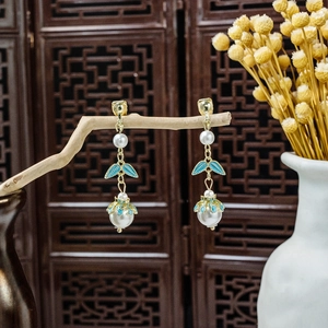 Detailed shot of long tassel pearl earrings with blue enamel leaves in vintage oriental style
