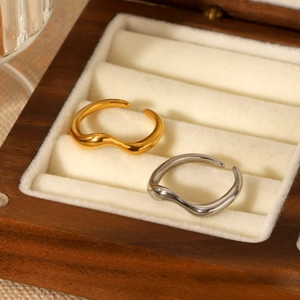Polished wave-shaped stainless steel open rings in gold and silver set on jewelry box