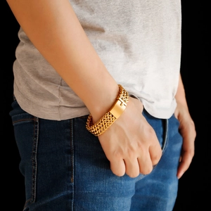 Detail of gold Cuban link chain with square buckle worn by male model on black background