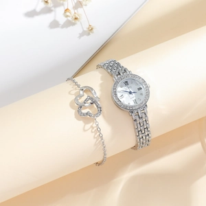 Close-up of silver quartz watch and heart bracelets with rhinestones set on paper