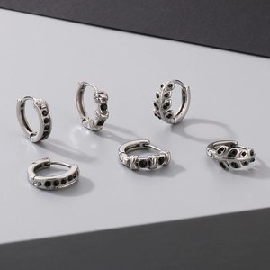 Detailed shot of silver hoop earrings featuring black stones and cross-etched textures