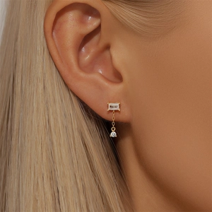 Macro side view of a gold infinity stud earring with marquise-cut zircon on a model ear