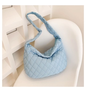Detail of light blue quilted nylon shoulder bag with fluffy crescent shape on white chair