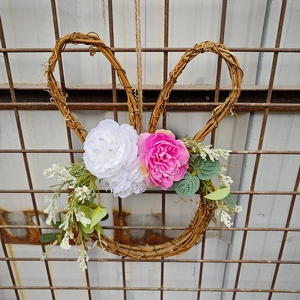 Detail of Easter bunny wreath with pink and white faux flowers on natural rattan
