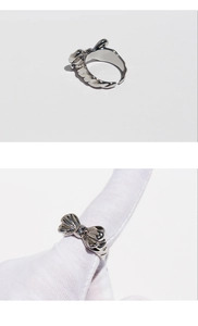 Detailed view of silver bow-shaped metal ring with textured surface and adjustable open fit