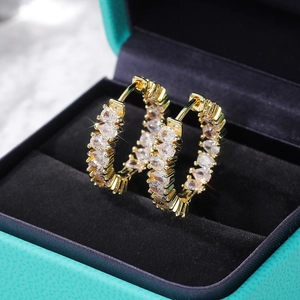 Macro detail of gold-plated hoop earrings with pear-cut AAA zircons on a jewelry box