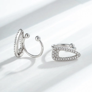 Silver geometric U-shaped ear cuffs with zircon inlays on textured white background