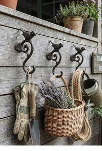 Detalle de tres ganchos de pared de hierro fundido vintage con pájaros en bronce