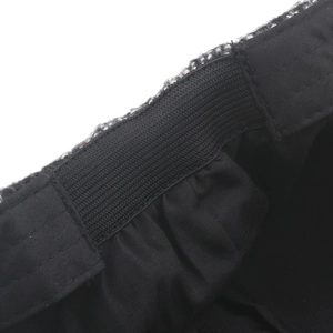 Close-up of the elastic adjustment strap and tweed fabric on the newsboy cap's back