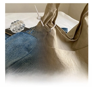Detail of a white cookie-shaped silicone bag charm with bead lanyard on canvas tote
