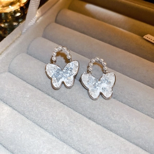 Detail of silver butterfly earrings with faux pearls and sparkling crystal inlay on velvet