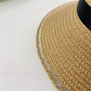 Detailed view of women's straw sun hat featuring lace brim edges and black ribbon texture