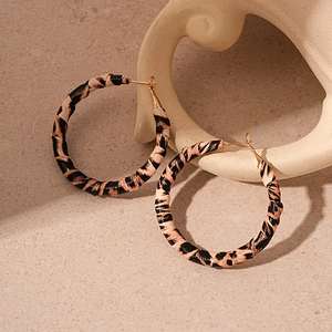 Macro detail of leopard print fabric wrapped hoop earrings with golden metal texture