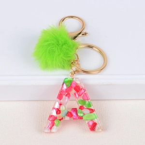 Detail of letter A resin keychain with colorful stones, green pompom and gold hardware