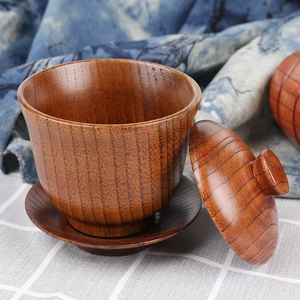Handcrafted brown jujube wood tea bowl set with lid and saucer on a rustic fabric background
