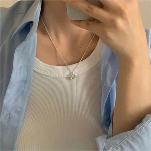 Detail view of a 925 sterling silver twisted heart pendant necklace on a model
