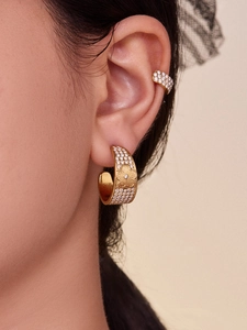 Detail of gold clover hoop earrings with pavé crystals on a model for a luxury look