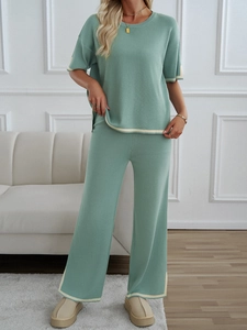 Detail view of light green knitted two-piece set with elegant beige striped trims on the hem