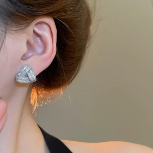 Detailed close-up of zircon triangle cross earrings on model for an elegant luxury style