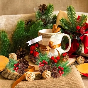 Close-up of rustic ceramic mug with burlap, ribbon, cedar pendant and cinnamon sticks