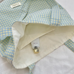 Detail of checkered canvas tote bag interior with inner pocket and woven brand label