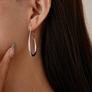 Close-up of silver hollow teardrop earring on model showing minimalist U-shaped design
