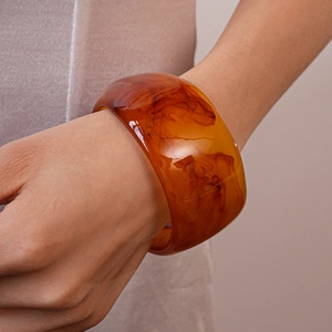 Detail view of a wide amber resin bangle with dark brown tortoiseshell marbled patterns