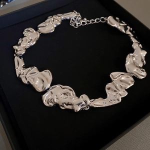 Irregular silver metal necklace featuring melted texture design in a black jewelry box