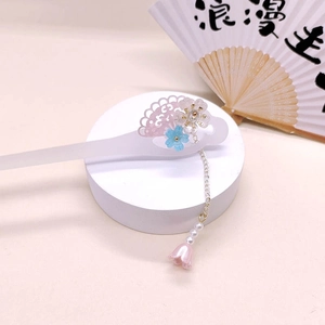 Close-up of acetic acid hair stick with floral design, tassels, and pearl accents