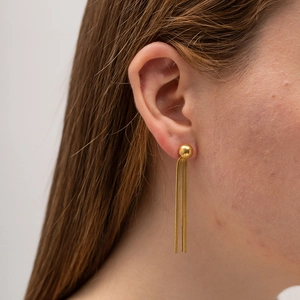 Close-up of minimalist golden tassel spherical earrings worn by a female model
