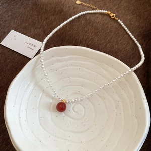 Elegant pearl necklace with red bead pendant in a vintage minimalist Chinese style