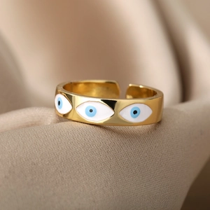 Detailed close-up of golden evil eye open ring on elegant champagne satin fabric