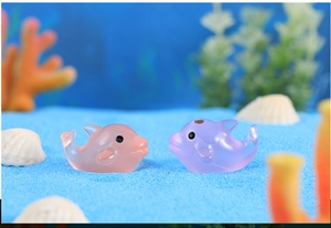 Detailed macro view of pink and purple resin dolphin figurines on blue decorative sand