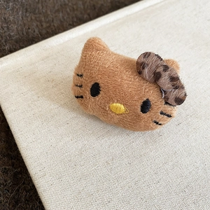 Detailed macro view of a brown flocked cat brooch featuring a leopard print bow tie