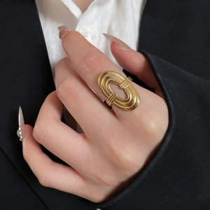 Close-up of a stacked oval geometric gold ring on finger with elegant black attire