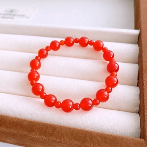 Macro detail of red agate beaded bracelet with alternating round stones in a jewelry box