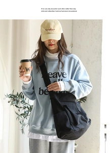 Lifestyle shot of large black canvas messenger bag worn by a model in casual city style