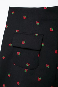 Détail de la poche d'un blazer noir avec des motifs de fraises brodées en gros plan