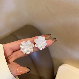 Detail shot of white flower tassel earrings with pearls and crystals held in hand