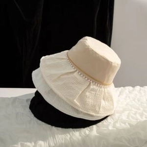 Détail de bobs empilés en coton beige, blanc et noir avec bordure élégante en perles