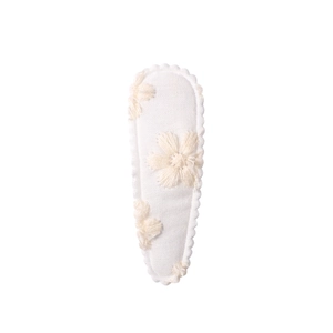 Close-up of cream floral fabric hair clip with 3D embroidery on a white background