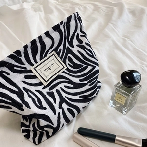 Retro zebra print corduroy makeup bag with label on soft white fabric background